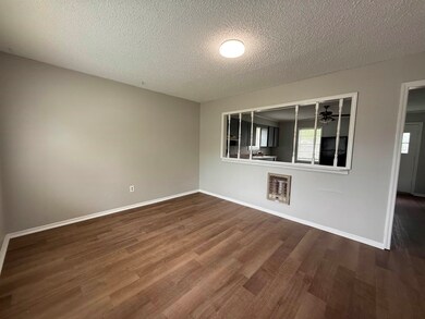 Spare room with dark wood-style floors, baseboards, a wealth of natural light, and a textured ceiling