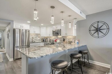 Kitchen with a breakfast bar area, stainless steel appliances, a peninsula, dark wood-type flooring, and recessed lighting