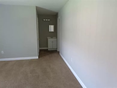 Carpeted spare room featuring baseboards