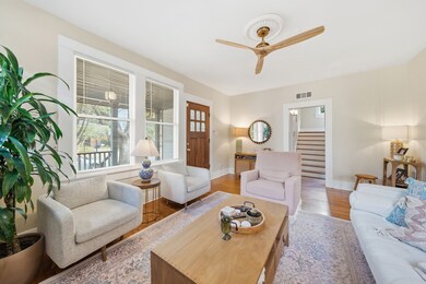 This inviting living room features warm hardwood floors and abundant natural light from large windows. 