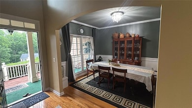 Dining area with arched walkways, wood finished floors, and ornamental molding