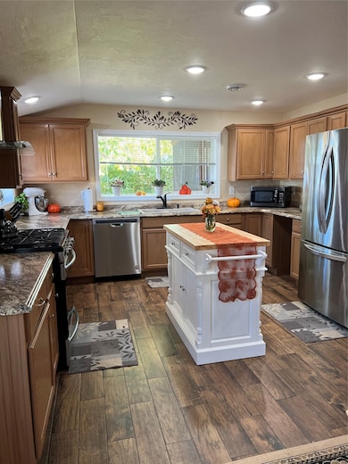 Kitchen with decorative backsplash, refrigerator, range, dishwasher, and dark wood-style floors