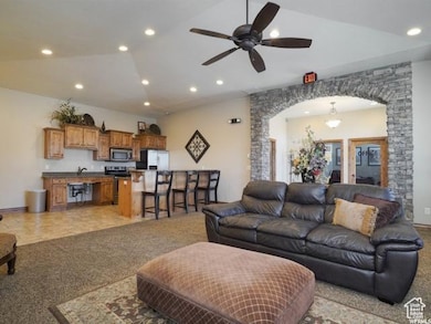 Living room with recessed lighting, light colored carpet, a ceiling fan, arched walkways, and lofted ceiling