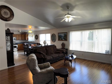 Living area with light wood-type flooring, vaulted ceiling, and a ceiling fan
