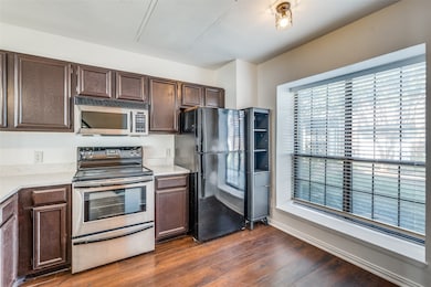 Kitchen featuring appliances with stainless steel finishes, dark brown cabinets, and dark wood-style floors