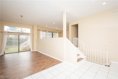 Tiled empty room featuring a chandelier and recessed lighting