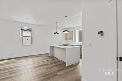 Kitchen featuring light wood-style flooring, hanging light fixtures, plenty of natural light, recessed lighting, and light stone counters