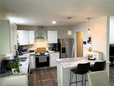 Kitchen featuring wall chimney exhaust hood, stain