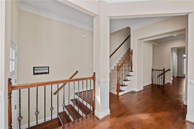 Staircase with crown molding and wood-type floorin