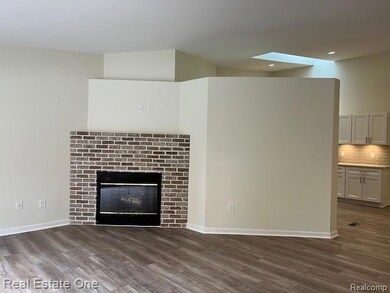 Unfurnished living room featuring dark wood finished floors, a brick fireplace, and a skylight