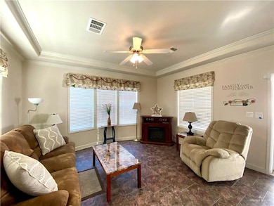 Living room with a fireplace, ceiling fan, and crown molding