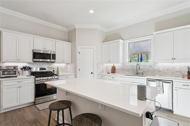 View of the kitchen from the hallway.  Stainless appliances, upgraded quartz counter tops and beautiful backsplash.