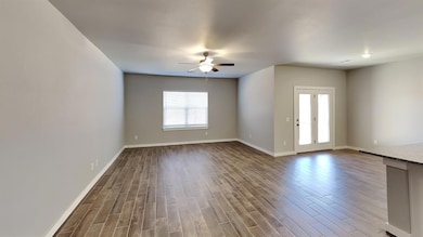 Unfurnished room with a ceiling fan, dark wood-style floors, and baseboards