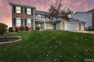 Twilight view of front facade with a front lawn, brick siding, concrete driveway, covered porch and an attached garage