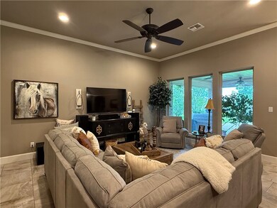 Living room with a ceiling fan, crown molding, and