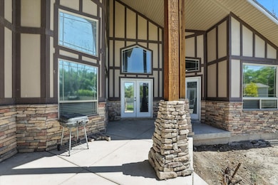 View of exterior entry with stone siding, french doors, and board and batten siding