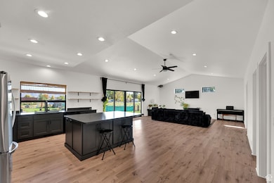 Kitchen featuring a kitchen breakfast bar, dark cabinets, freestanding refrigerator, light wood finished floors, and open shelves