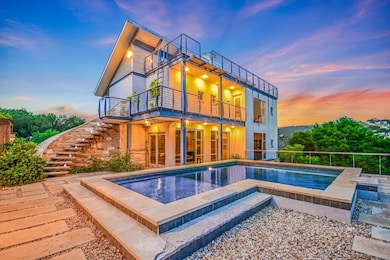 Back of property at dusk featuring a balcony, sta