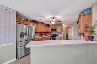 Kitchen featuring stainless steel appliances, gas cooking a peninsula, light countertops, backsplash, and ceiling fan and breakfast bar