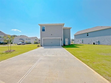 View of front of home with an attached garage, concrete driveway, and a front yard
