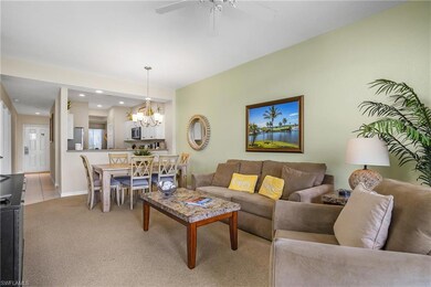 Living room featuring light colored carpet, baseboards, and ceiling fan with notable chandelier