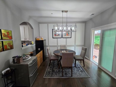Dining area featuring dark wood-type flooring, a chandelier, and arched walkways