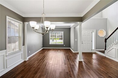 Foyer featuring ornamental molding, dark wood-type flooring, ornate columns, a chandelier, and stairs