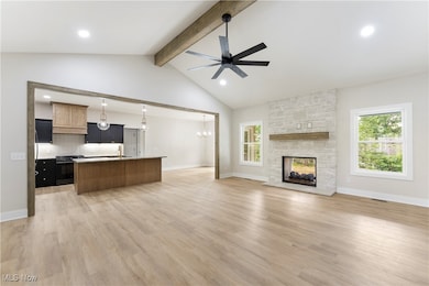 Unfurnished living room featuring ceiling fan, healthy amount of natural light, a stone fireplace, recessed lighting, and light wood-style flooring