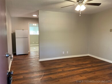 Empty room with a ceiling fan, dark wood-style flo