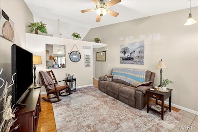 Living room with lofted ceiling, a ceiling fan, and light wood-type flooring