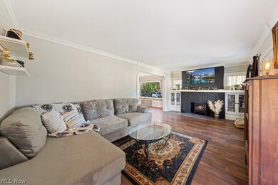 Living room with dark wood-type flooring, a tiled fireplace, and crown molding