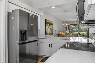 Kitchen with stainless steel refrigerator with ice dispenser, range, white cabinets, decorative light fixtures, and wood finished floors