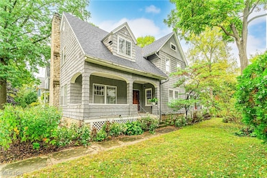 New England style home featuring a shingled siding, covered porch, and front yard