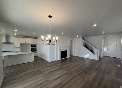 Unfurnished living room featuring a chandelier, recessed lighting, dark wood finished floors, and stairway