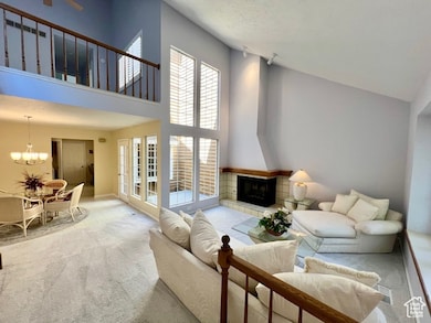 Living area featuring carpet, a fireplace, a chandelier, and a towering ceiling