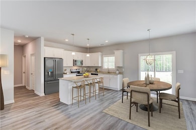 Kitchen featuring stainless steel appliances, a sink, a kitchen island, white cabinets, and a chandelier