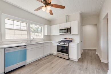 Kitchen with appliances with stainless steel finishes, white cabinets, light wood-type flooring, wooden ceiling, and a ceiling fan