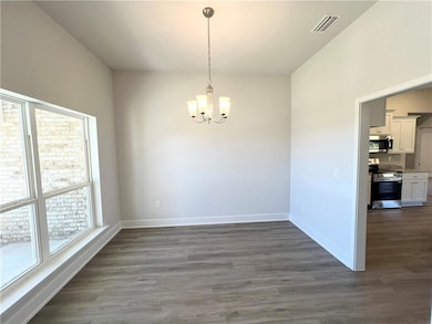 Unfurnished dining area with dark wood finished floors and a chandelier