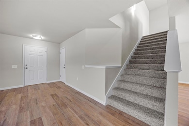 Foyer entrance with stairway, baseboards, and woo