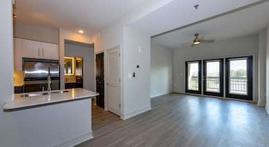 Kitchen with white cabinets, stainless steel fridge, kitchen peninsula, ceiling fan, and wood-type flooring
