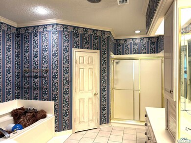 Full bath featuring crown molding, tile patterned flooring, a stall shower, a textured ceiling, and a garden tub
