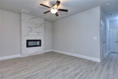 Unfurnished living room with light wood-style flooring, a premium fireplace, and a ceiling fan