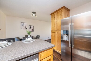 Kitchen with appliances with stainless steel finishes, dark wood-type flooring, light stone counters, and light brown cabinetry