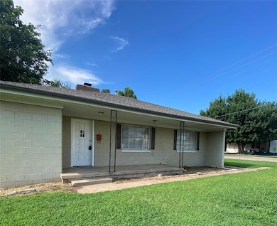 View of front of property featuring a front lawn, concrete block siding, and a porch