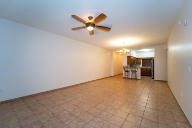 Unfurnished living room with a chandelier, a ceiling fan, and light tile patterned floors