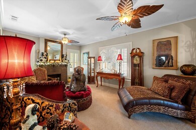 Carpeted living room with crown molding, a wealth of natural light, a brick fireplace, and ceiling fan