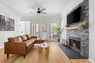 Living room with light wood-style flooring, a fireplace, and a ceiling fan