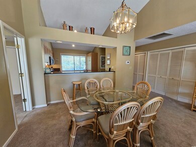 Carpeted dining room with a chandelier and high va