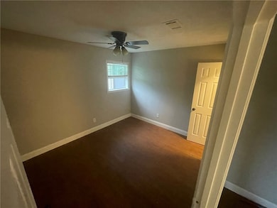 Empty room with a ceiling fan and dark wood-type flooring