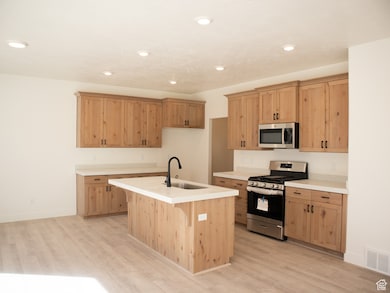 Kitchen with light wood stained cabinetry, GE appliances, quartz countertops, and upgraded kitchen faucet.